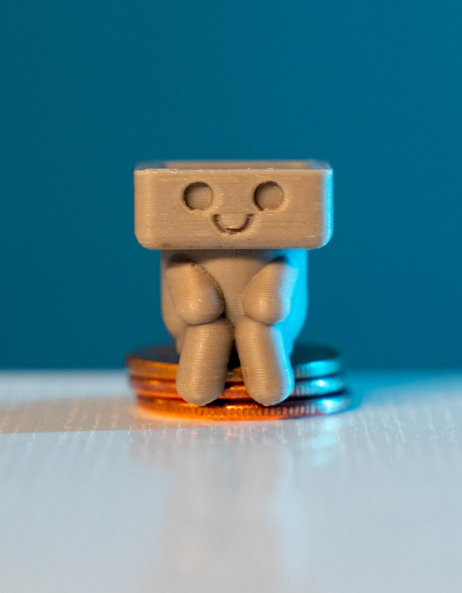 A cute 3D printed figure sitting on coins